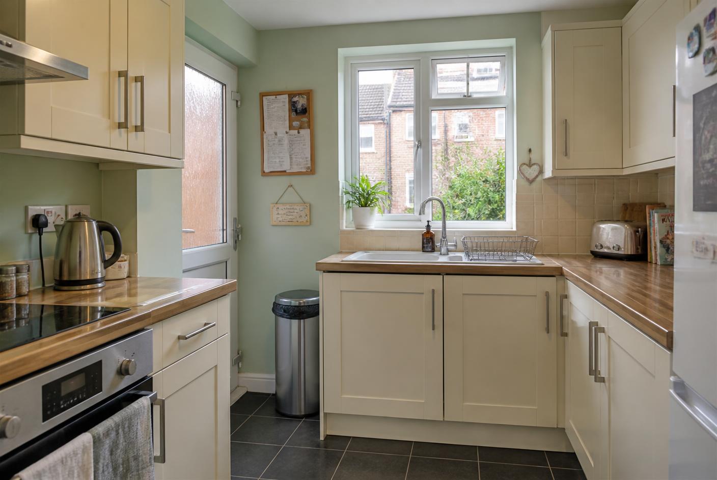 The same kitchen with clear worktops, an empty sink and wiped surfaces